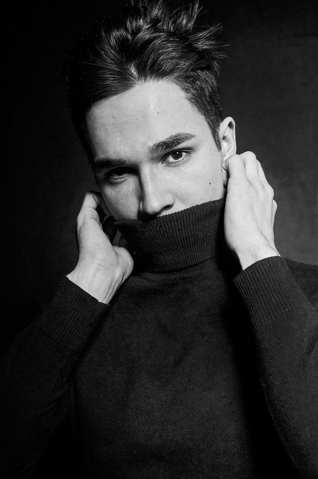 Studio portrait of a confident young man in a dark sweater